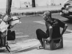 Photo by Hobi industri grayscale photo of man sits on crate beside road