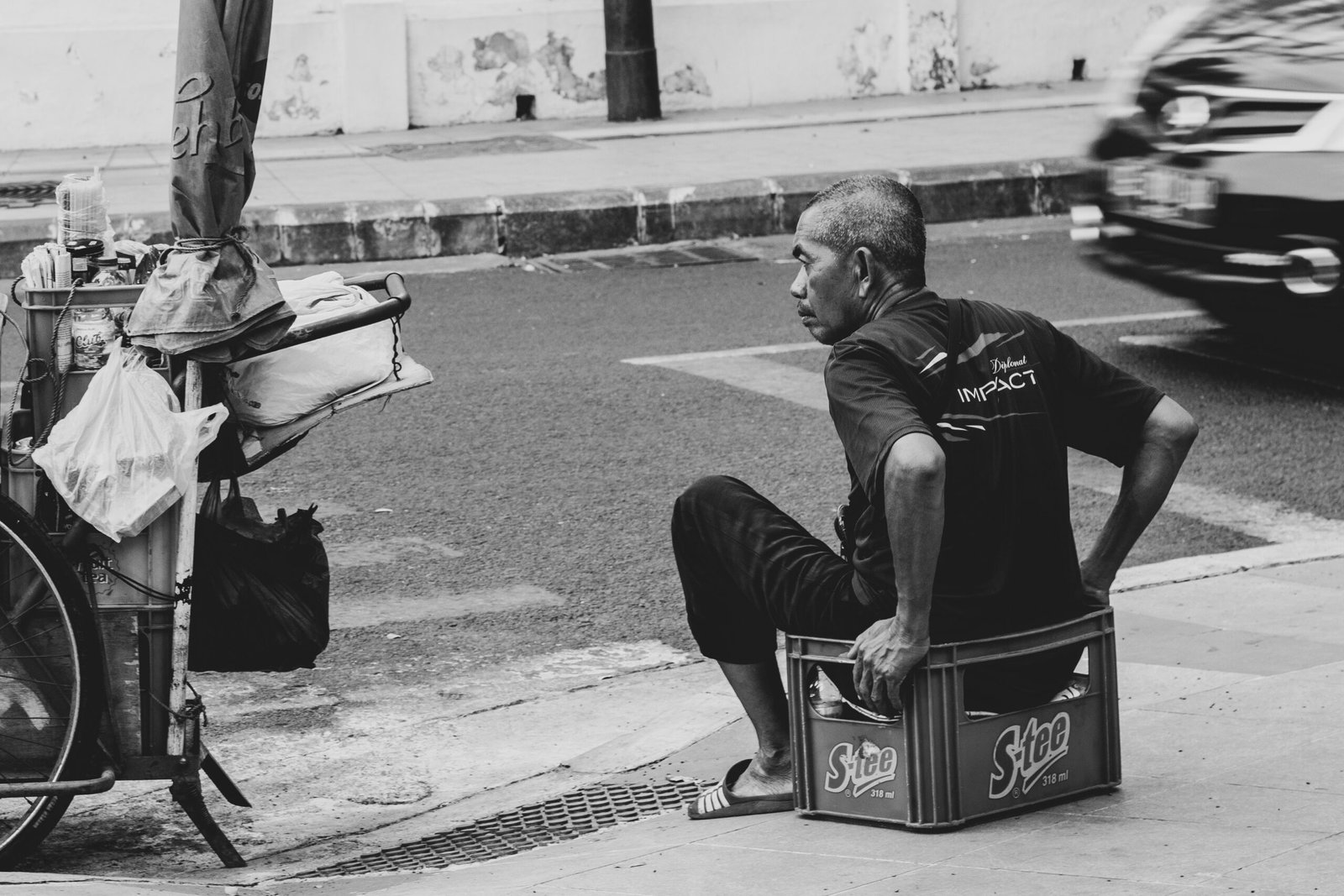 Photo by Hobi industri grayscale photo of man sits on crate beside road